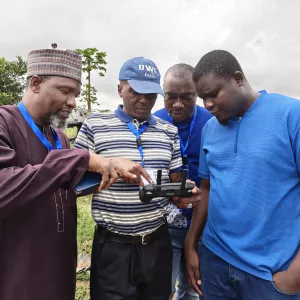Participants examine the drone controller during the field session, learning flight operations and data capture protocols.