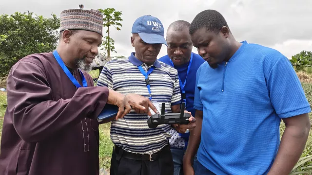 Participants examine the drone controller during the field session, learning flight operations and data capture protocols.